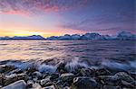 The waves breaking on the stones beach during sunset. Nordmannvik, Kafjord, Lyngen Alps, Troms, Norway, Lapland, Europe.