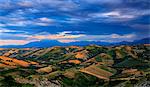 Hills overlooking Majella group illuminated by the sun at sunset. Calanchi of Atri, Abruzzo, Italy.