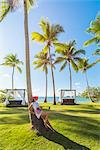 Playa Moron, Las Terrenas, Samana Peninsula, Dominican Republic. Woman relaxing on a palm-fringed meadow (MR).