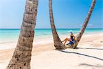 Juanillo Beach (playa Juanillo), Punta Cana, Dominican Republic. Woman under high palm trees on the beach (MR)