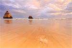 Pink sky at sunset on cliffs and sandy beach surrounded by the clear sea Praia Dos Tres Irmaos Portimao Algarve Portugal Europe