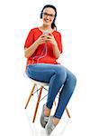 Happy woman sitting on a chair and listen music on her phone, isolated over white background