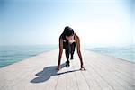 Young beautiful sportive girl preparing to run over seaside.