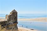 Beachgoers crossing a lagoon formed by the low tide, and detail of a watchtower in Cacela Velha, Algarve, Portugal, Europe