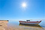 The sun shines above a small fishing boat on transparent lagoon water in Cacela Velha, Algarve, Portugal, Europe