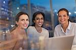 Portrait smiling, confident businesswomen working ate at laptop in conference room meeting