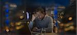 Tired businessman yawning with head in hands, working late in office at night