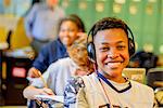 Portrait of teenage schoolboy wearing headphones at classroom desk