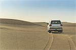 Off road vehicle driving over desert dunes, Dubai, United Arab Emirates