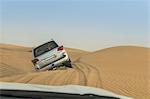 Off road vehicle driving over steep desert dunes, Dubai, United Arab Emirates