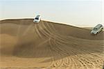 Off road vehicles driving down desert dunes, Dubai, United Arab Emirates