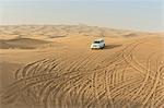 Off road vehicle driving down desert dunes, Dubai, United Arab Emirates