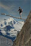 Mature male climber stepping across wire rope bridge, Jegihorn, Valais, Switzerland