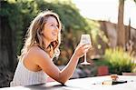 Young woman sitting outdoors, holding wine glass, smiling