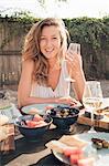 Portrait of young woman, outdoors, sitting at table, holding wine glass