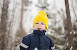 Boy in yellow knit hat in snow covered forest