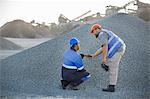 Two quarry workers in quarry, checking aggregate