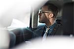 Businessman sitting in back of car, holding smartphone