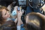 Three young women in car, looking at sat nav, overhead view