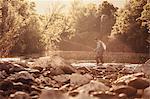 Fisherman ankle deep in sunlit river, Mozirje, Brezovica, Slovenia