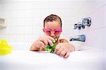 Girl wearing swimming goggles playing with toys in bath