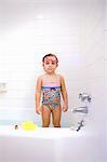 Portrait of girl wearing swimming goggles standing in bath