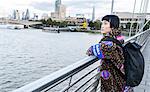 Stylish young woman looking out from millennium footbridge, London, UK