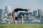Teenage girl and young man, outdoors, balancing on hands in yoga position