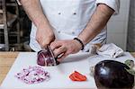 Cropped view of chef slicing red onion