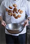 Cropped view of chef tossing doughnuts and sugar in mixing bowl