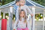 Girls and boy at preschool, portrait at top of playground slide in garden