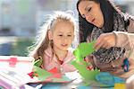 Mid adult woman helping young girl with crafting activity