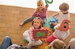 Group of children, outdoors, holding up foam shapes and numbers, elevated view