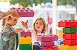 Two young children, outdoors, playing with foam building blocks