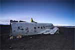 Man on the top of the abandoned US Navy DC plane on the beach of Solheimasandur, Sudurland, Iceland, Europe