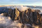 Aerial view of the mountain range of Odle surrounded by clouds. Dolomites Val Funes Trentino Alto Adige South Tyrol Italy Europe