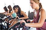 Young woman using elliptical bike in exercise class