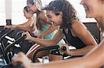 Smiling young woman using elliptical bike in exercise class