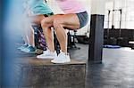 Muscular young woman doing jump squats on box in gym