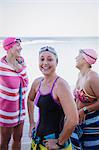 Portrait smiling, confident female open water swimmers drying off with towels at ocean