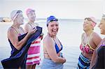 Portrait smiling female open water swimmers drying off with towels in ocean