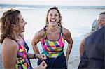 Laughing female open water swimmers talking on ocean beach