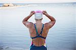 Female open water swimmer adjusting swimming goggles at ocean