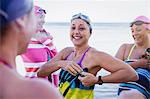 Smiling female open water swimmers drying off with towels on beach