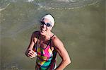 Portrait laughing, confident female open water swimmer wading in ocean