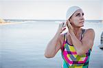 Female open water swimmer adjusting swimming cap at ocean