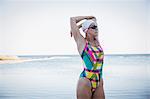 Female open water swimmer stretching arm at ocean