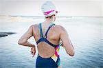 Female open water swimmer running into ocean