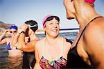 Laughing female open water swimmers talking in sunny ocean