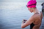 Female open water swimmer checking smart watch at ocean